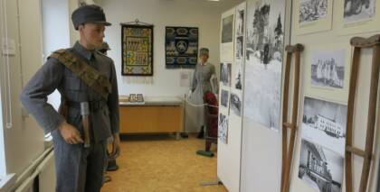 Näyttelytila, jossa esillä sota-ajan asuihin puettuja mallinukkeja ja seinillä kuvia.